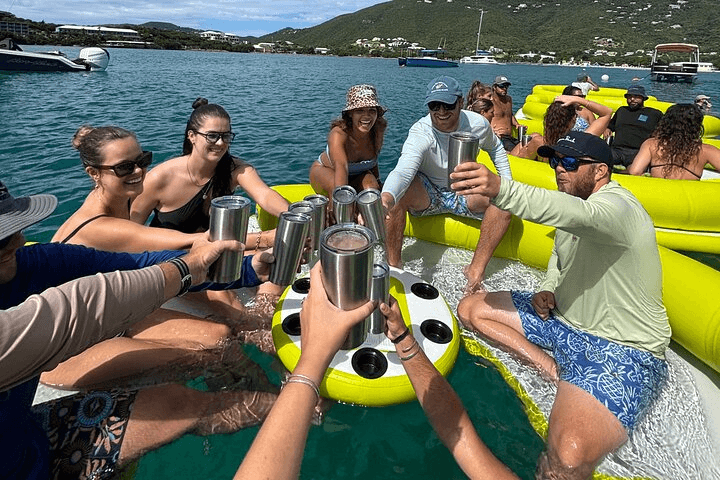 Guests cheersing drinks aboard the Taco Tug with turquoise Caribbean water in the background